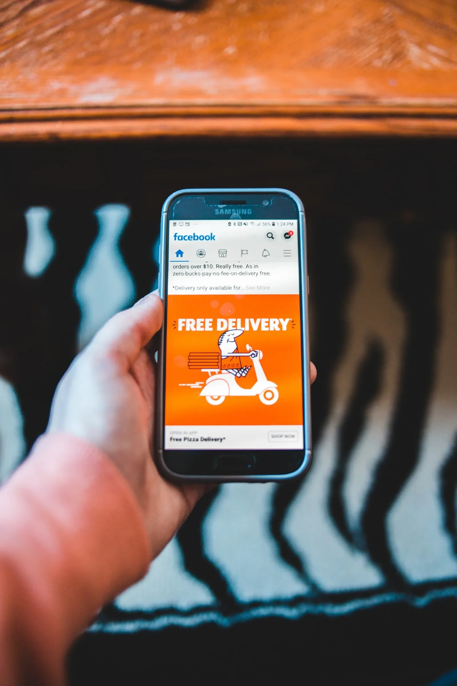 Hand holding a phone showing a Facebook ad offering free delivery