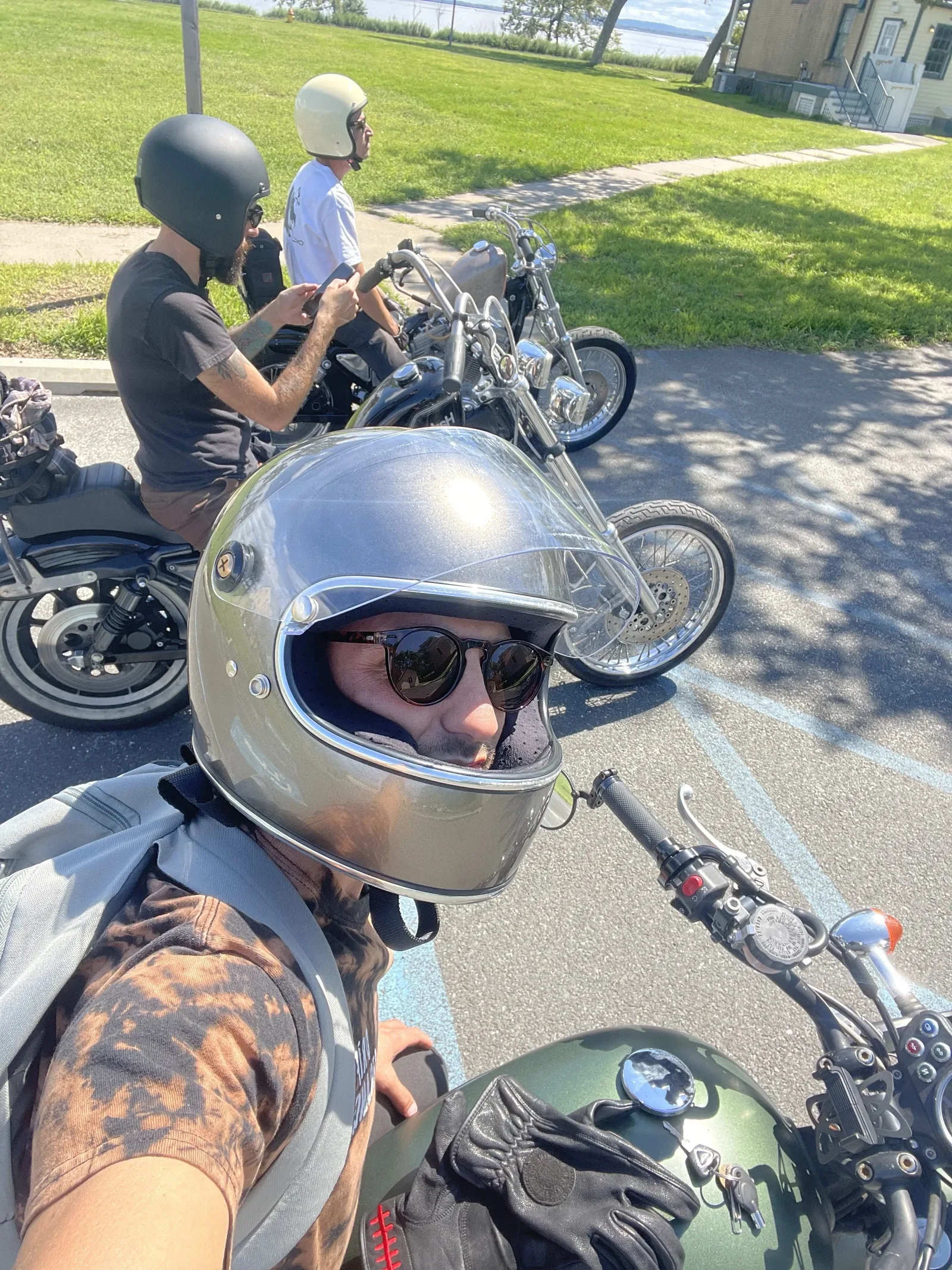 Mike Forgie in a motorcycle helmet taking a selfie with friends on motorcycles