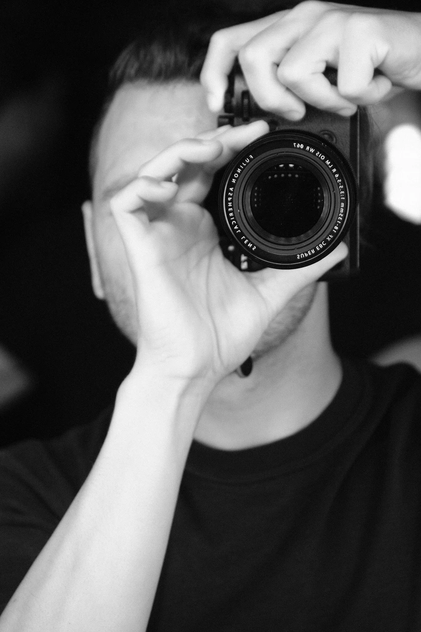 Black and white photo of Mike Forgie holding a camera up to his eye