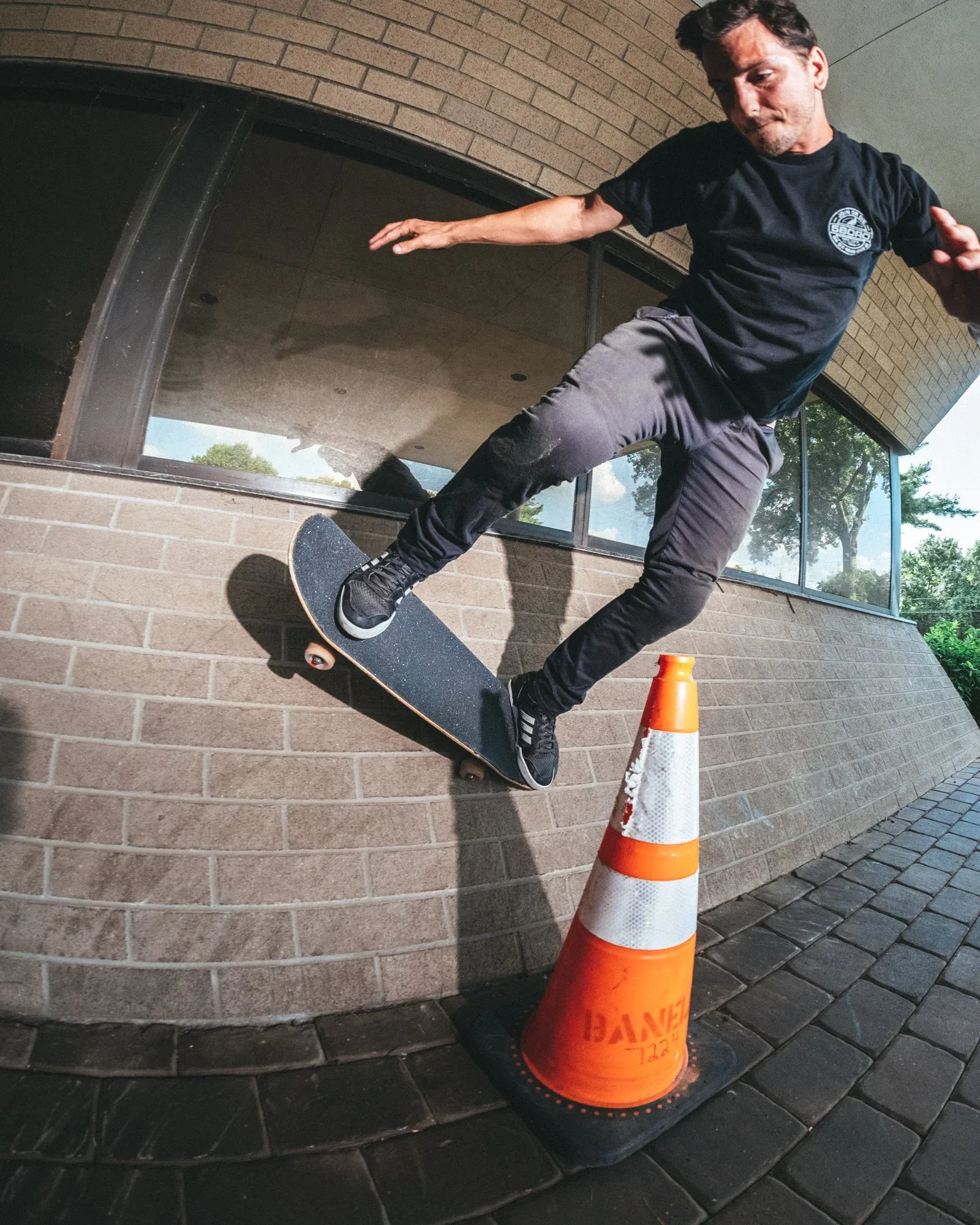 Mike Forgie riding a skateboard up a wall over a traffic cone